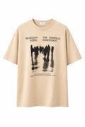 Beige graphic tee with abstract black figures and bold text, casual streetwear style