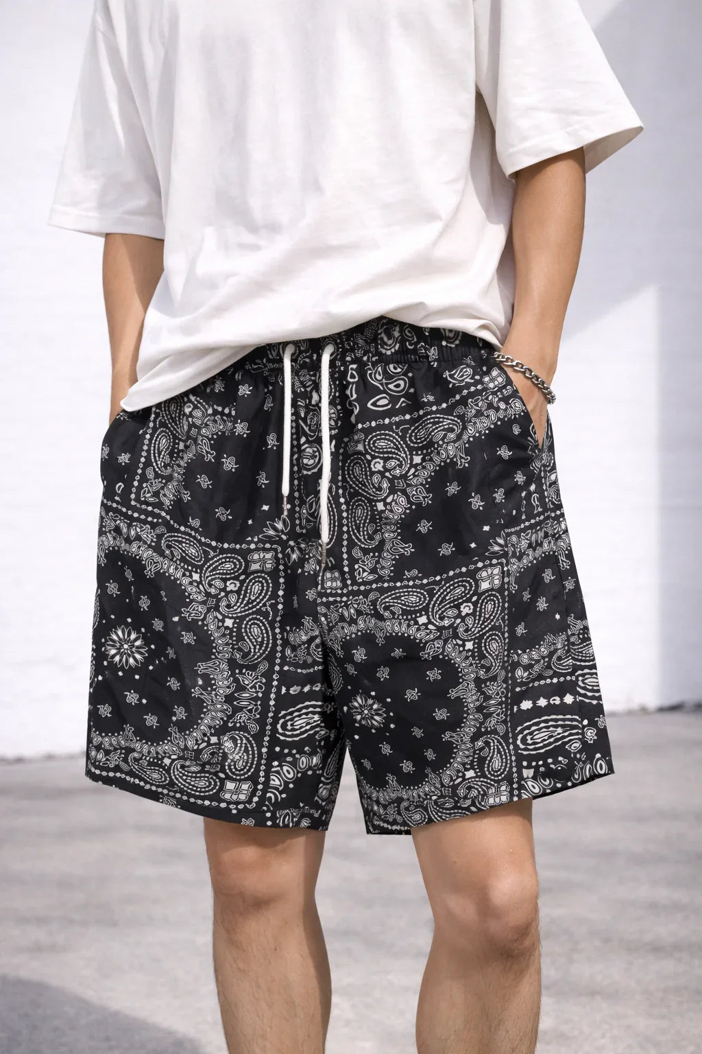Man wearing black bandana print shorts with white drawstring and a plain white t-shirt