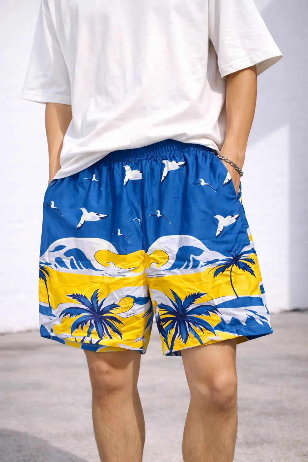 Blue and yellow tropical print shorts with palm trees, ocean waves, and seagulls
