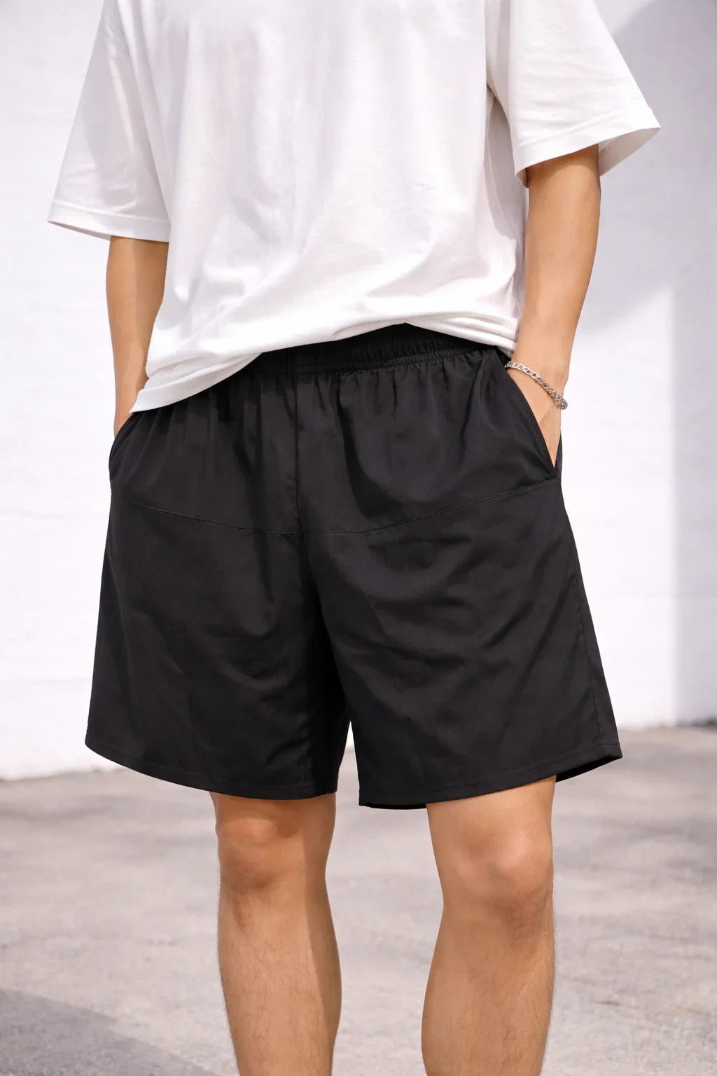 Man wearing black casual shorts with elastic waistband and white t-shirt outdoors