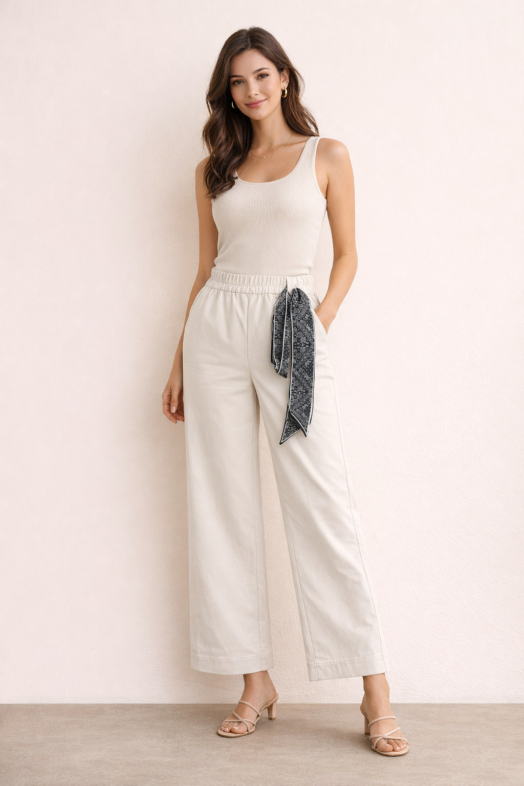 Woman wearing a white sleeveless top and wide-leg pants with a scarf.
