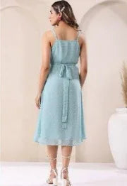 Back view of woman wearing light blue sleeveless midi dress with waist tie, casual setting