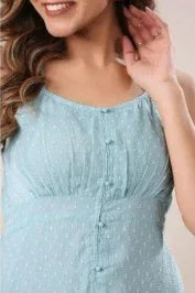 Woman wearing a light blue sleeveless dress with button details and a subtle dotted pattern