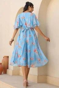 Woman wearing light blue floral midi dress with short sleeves and waist tie, outdoors