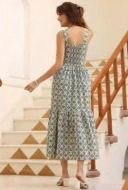 Woman in a sleeveless floral maxi dress with shirred bodice, walking up stairs indoors