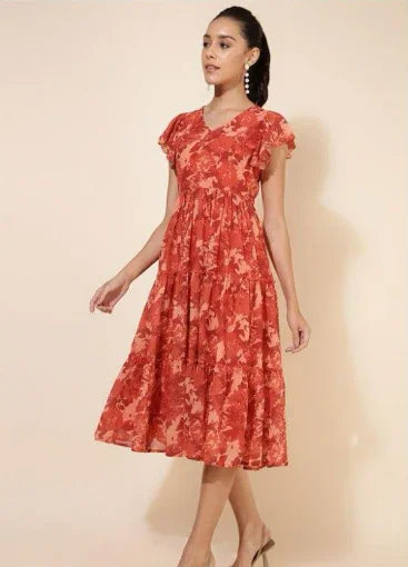 Woman wearing a red floral midi dress with ruffle sleeves, standing against beige background