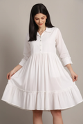 Model touching fabric of white tiered dress - showing soft cotton quality