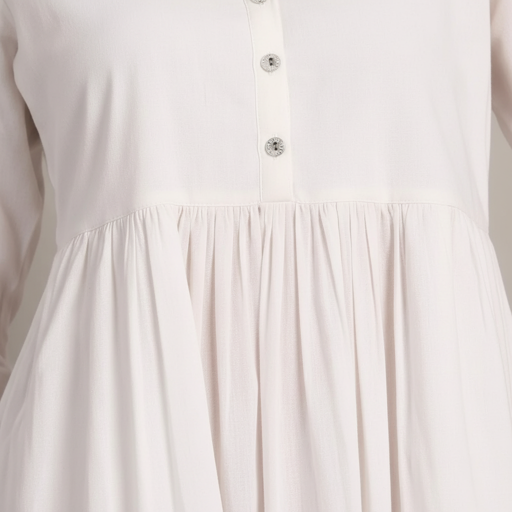 Close-up detail of white tiered dress showing gathered waist and ruffle layers