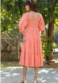Woman outdoors in a coral floral midi dress with puff sleeves and square neckline